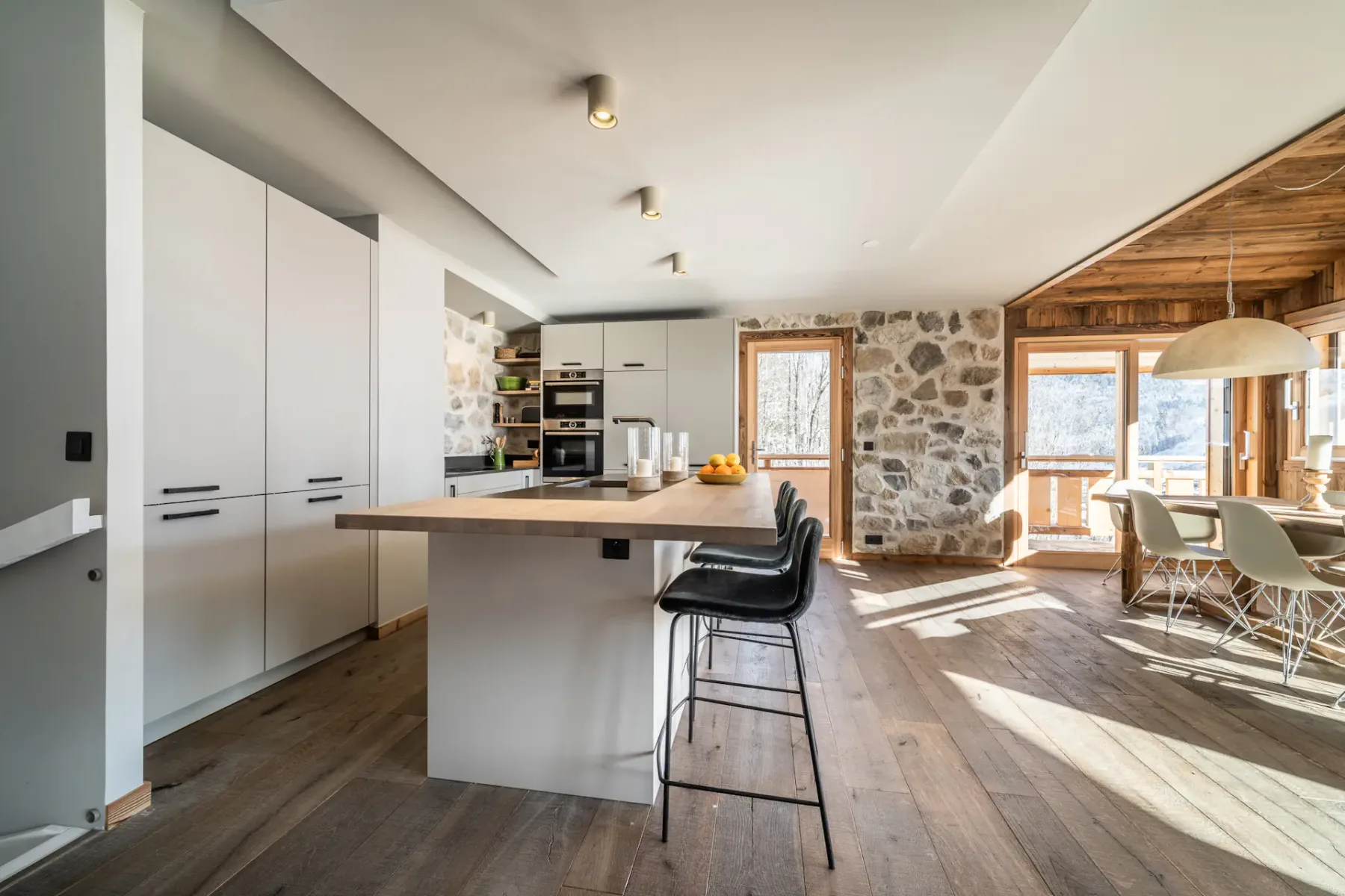 Una cocina abierta y comedor con una isla central y paredes de piedra.