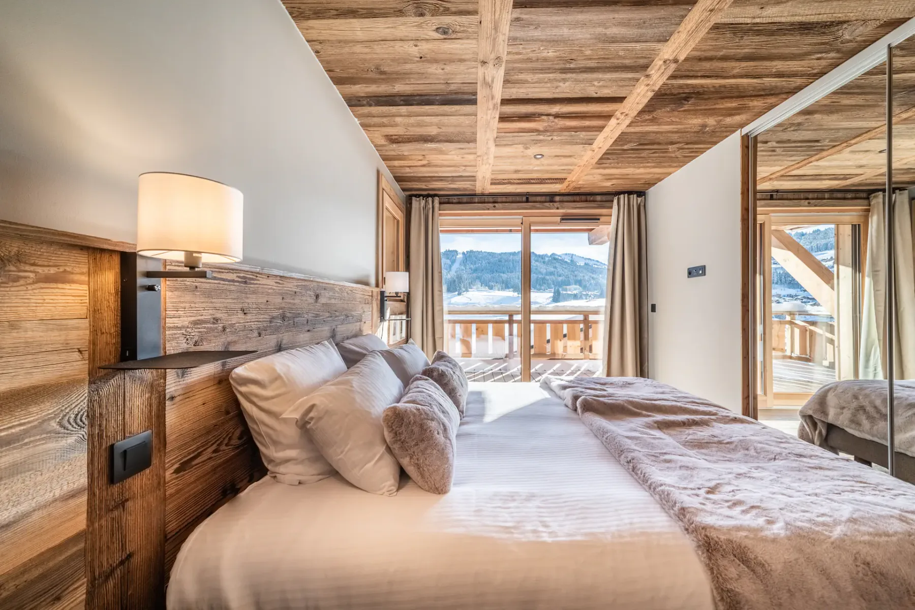 Un dormitorio con cama, techo de madera y puertas corredizas de vidrio que dan a un balcón.