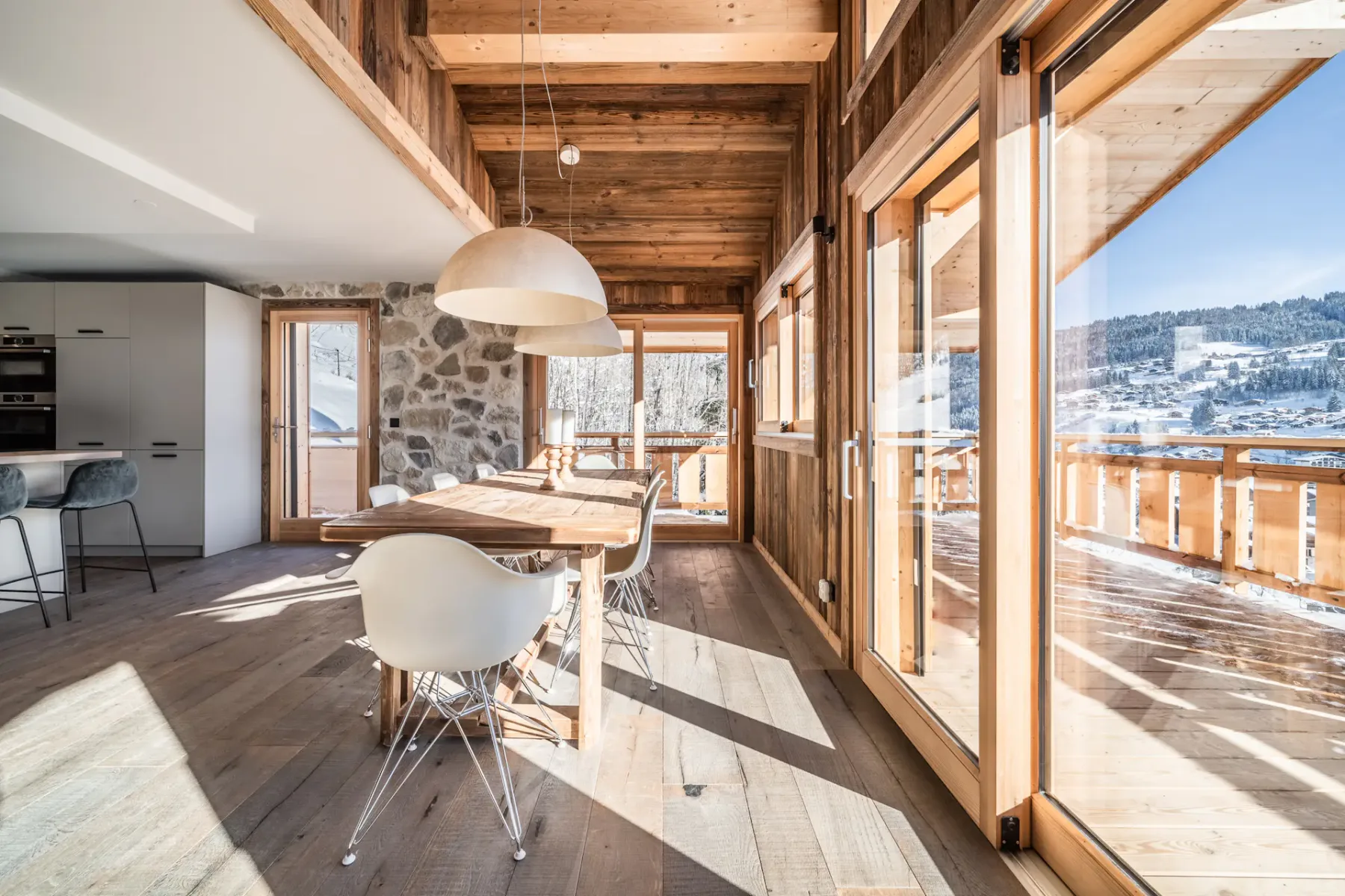 Un comedor luminoso con una mesa larga junto a grandes ventanales con vistas a un paisaje nevado.