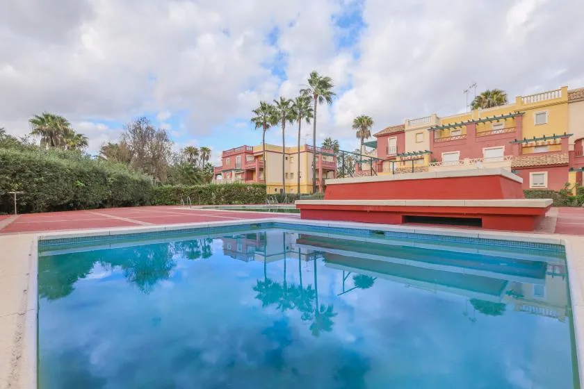 Shared amenity: An outdoor swimming pool reflects palm trees and colorful buildings.