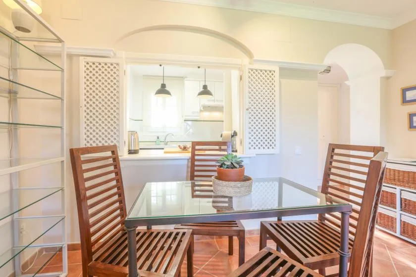 A dining area with a glass-top table and wooden seating.