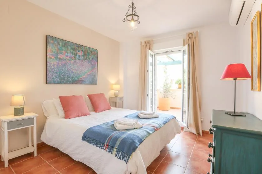 A bright bedroom with a bed dressed in white and blue bedding.