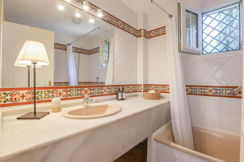 A bathroom with a sink, a large mirror, and a bathtub behind a curtain.