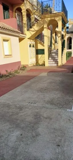 Shared amenity: Exterior walkway beneath a staircase beside a building.