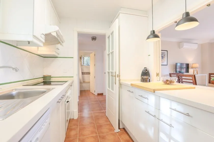 A bright kitchen with white cabinets opens onto a dining area.