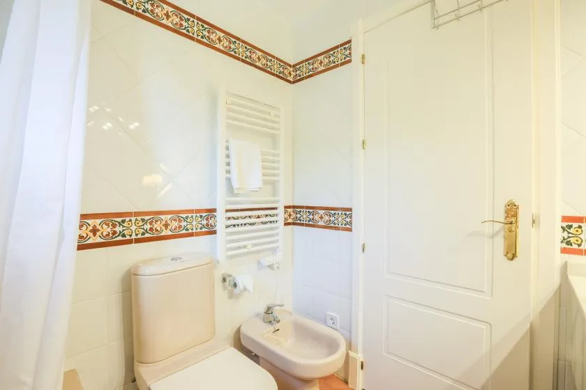 A tiled bathroom with a toilet, bidet, and white door.