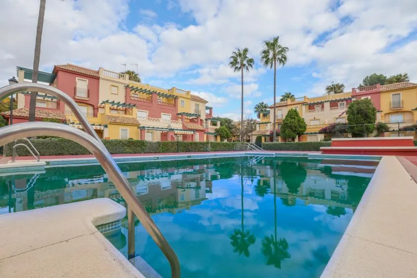 Shared amenity: A swimming pool sits among colorful residential buildings and palm trees.