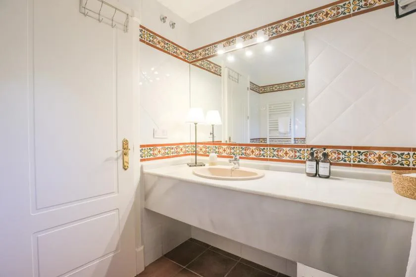 A bright bathroom features a sink vanity beneath a large mirror.