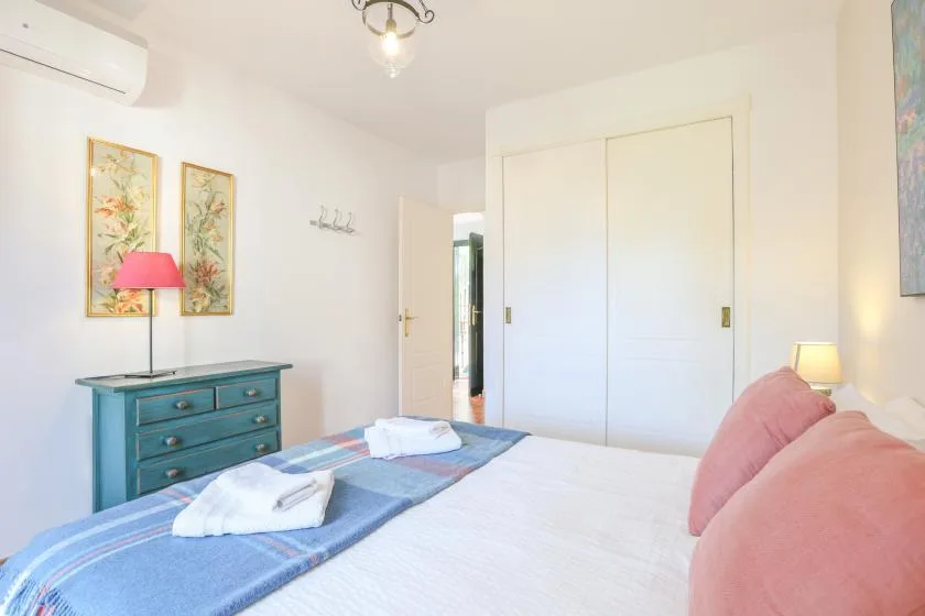 A bedroom with a bed, blue dresser, and framed wall art.