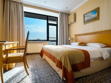 Espacio representativo del hotel: Un dormitorio con una cama, un escritorio y una ventana grande.