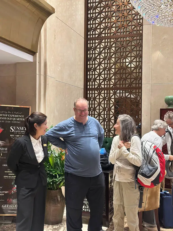 Representative hotel space: People talk beside a tall decorative screen in a hotel lobby.