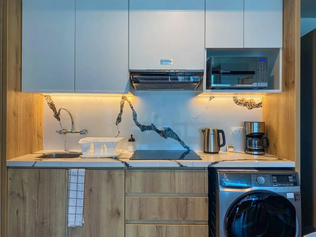 A compact kitchen with a sink, countertop appliances, and a washing machine.