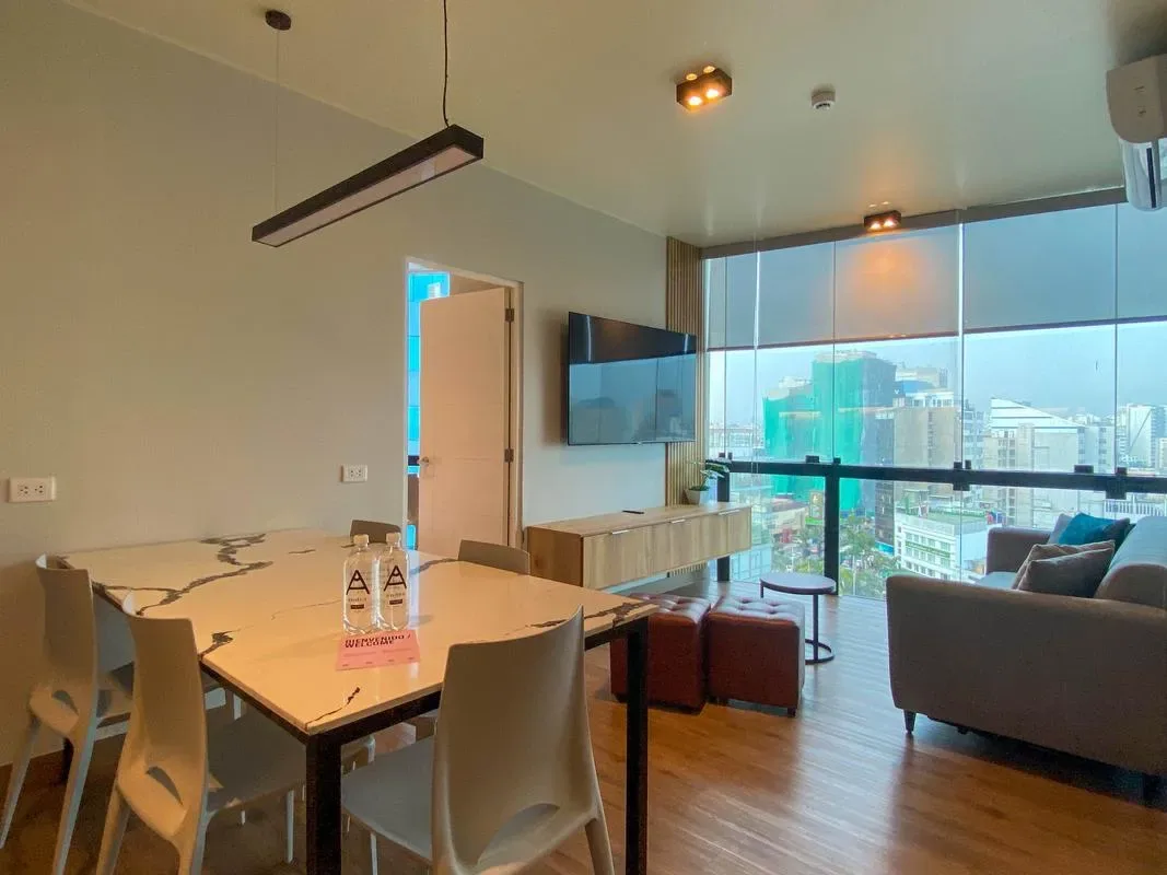 A bright open-plan living and dining area with large windows overlooking the city.