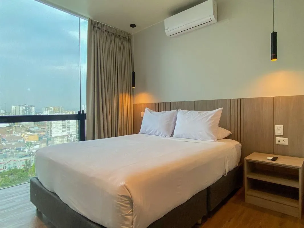 A bedroom with a neatly made bed beside a large window.
