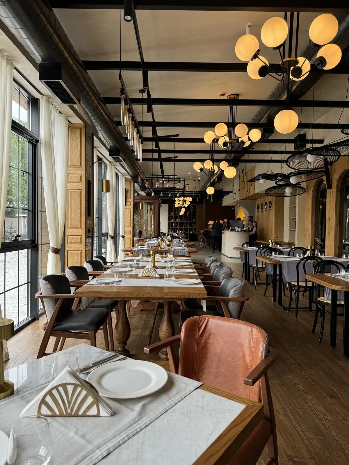 Espacio representativo del hotel: Un comedor con mesas largas, asientos dispuestos y lámparas colgantes.