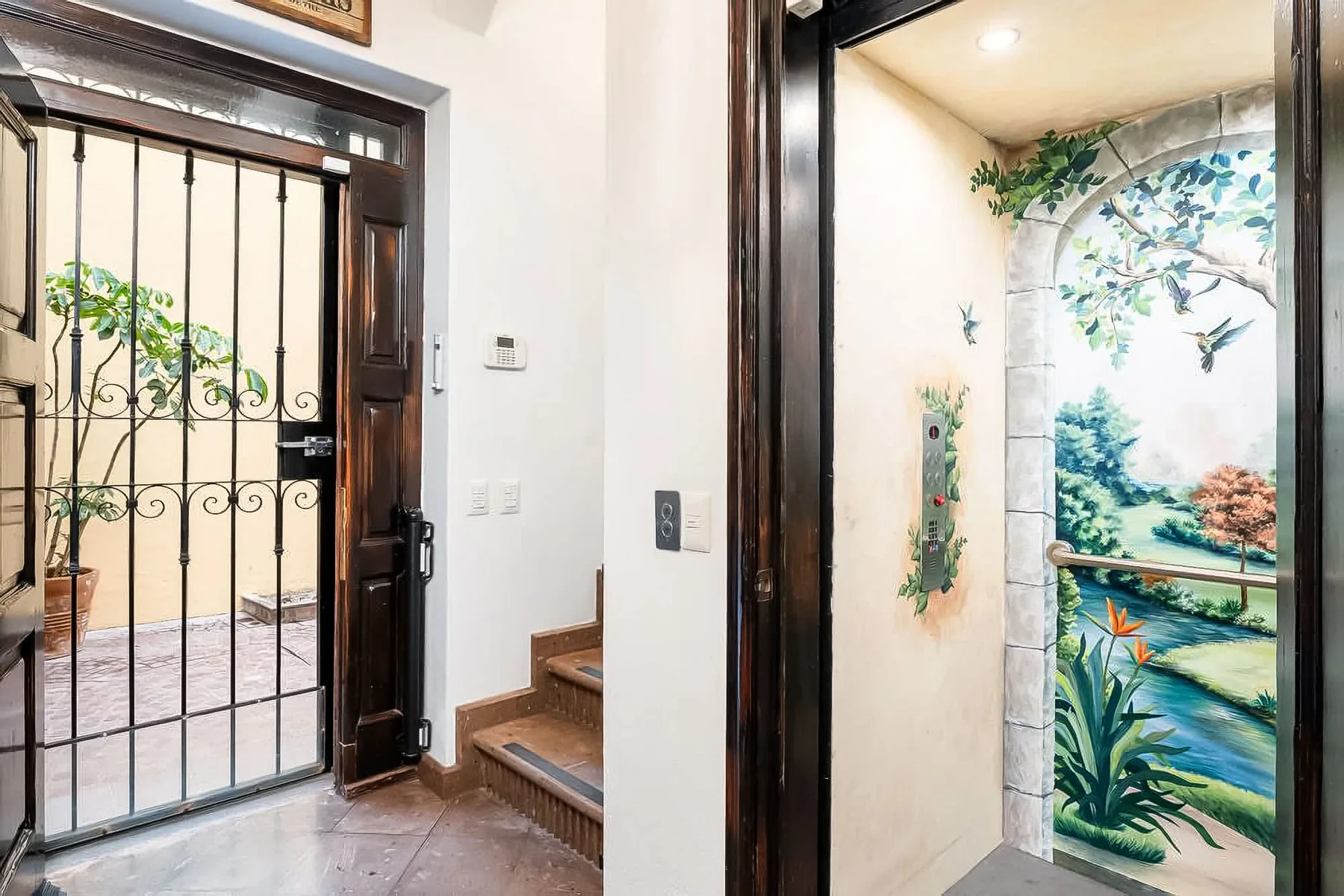 An entryway with a barred door beside a doorway painted with a garden mural.