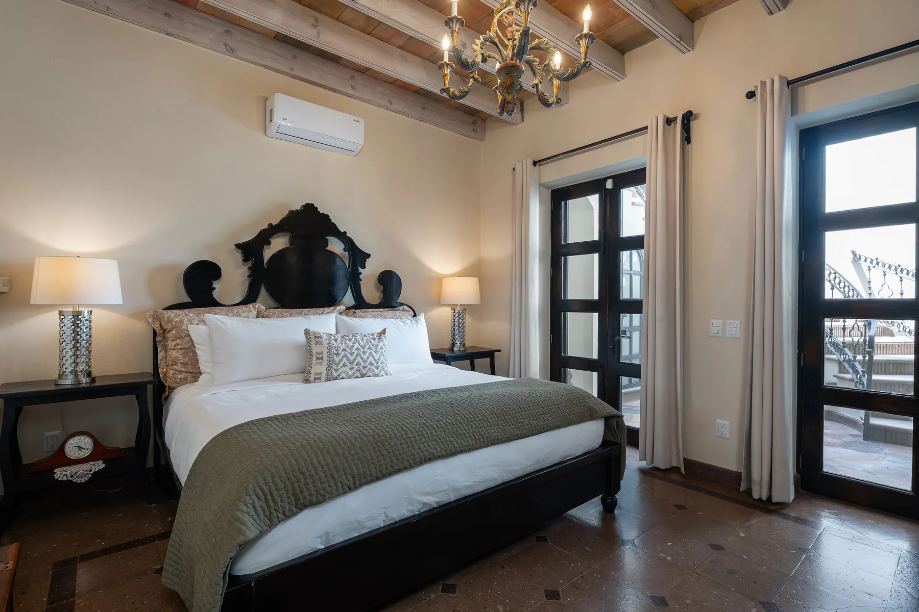 A bedroom with a large bed, bedside tables, and tall windows.