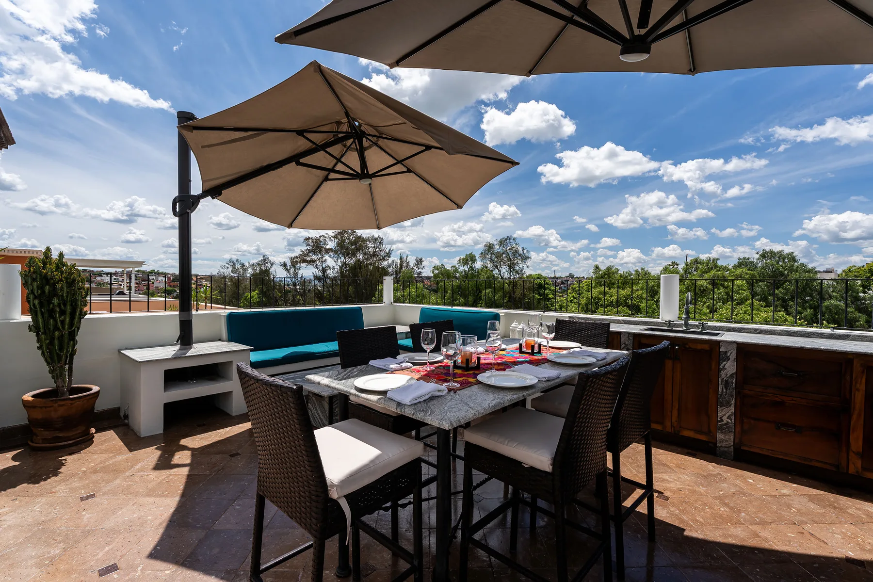A rooftop terrace dining area with a table and large sun umbrellas.