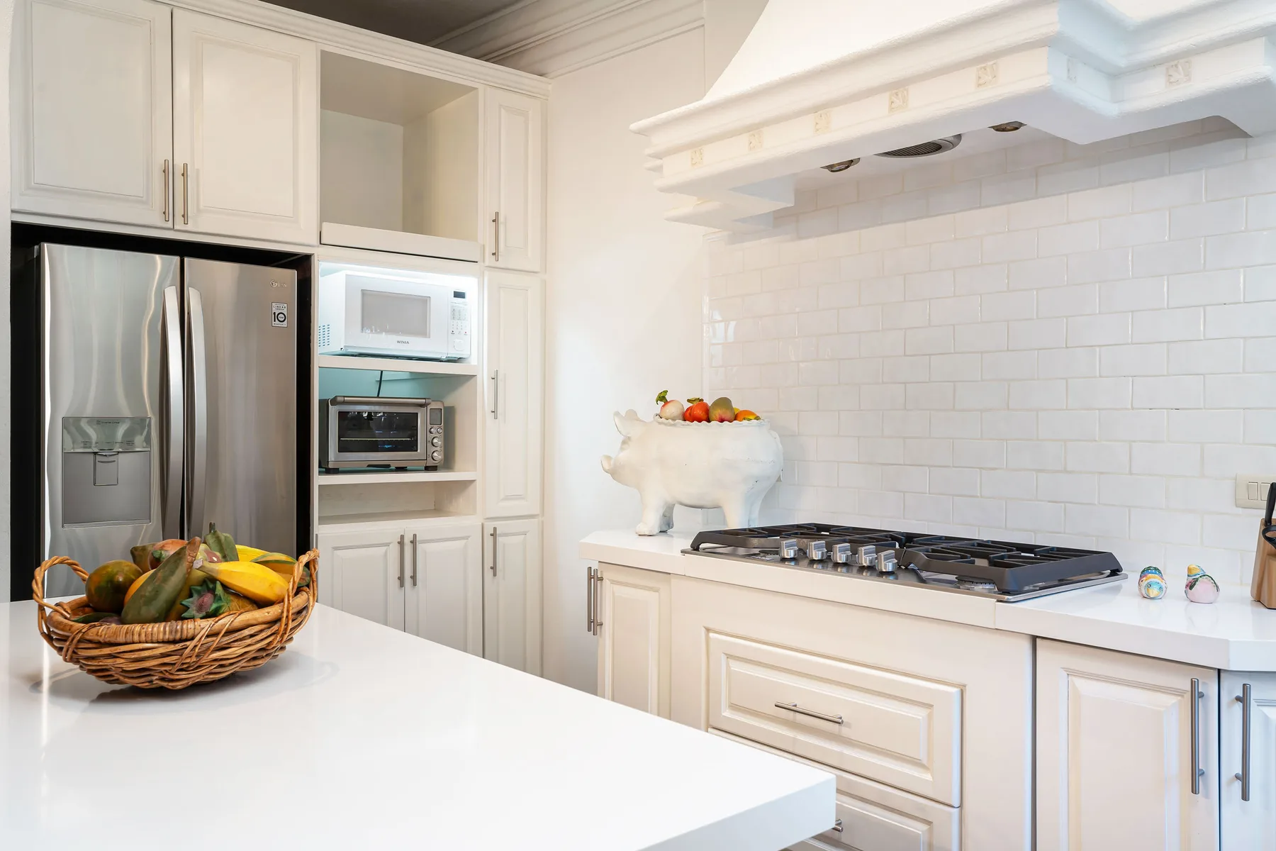 A bright kitchen with white cabinetry, stainless steel appliances, and a tiled backsplash.