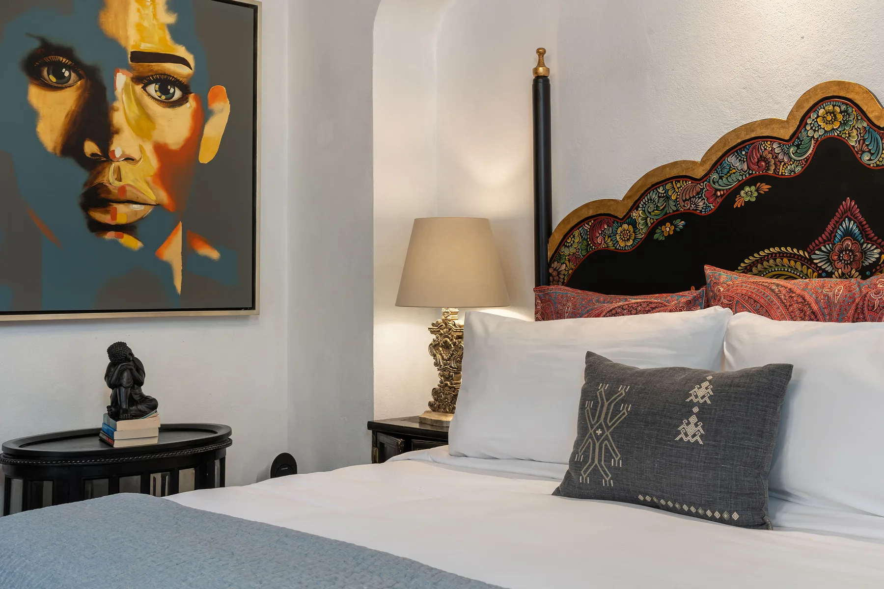 A bedroom with a neatly made bed and colorful artwork on the wall.