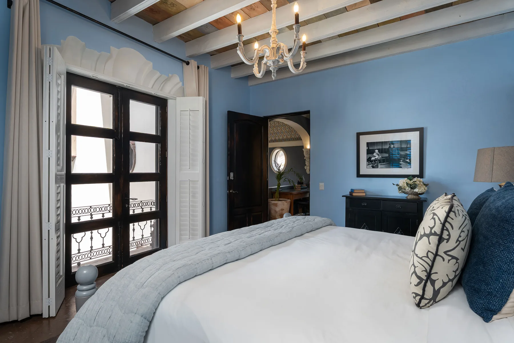 A bedroom with a large bed, blue walls, and tall windows.