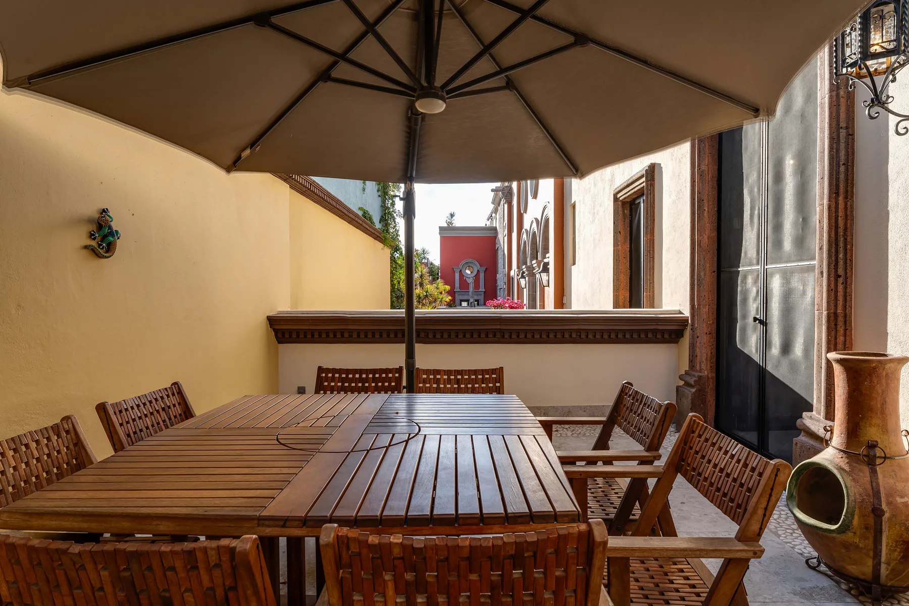 An outdoor dining area with a large wooden table and umbrella.
