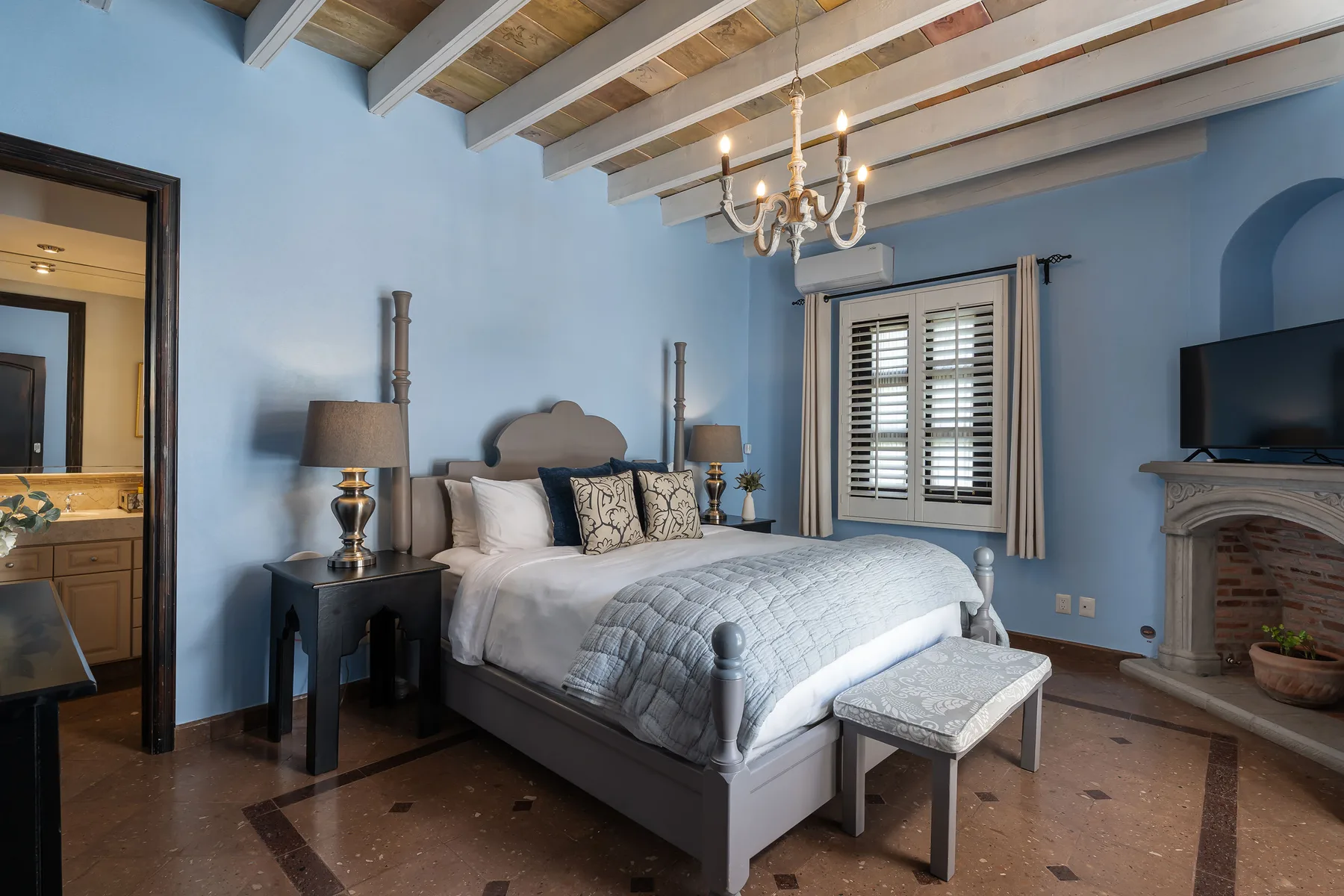A bedroom with a large bed, bedside tables, and a window with shutters.