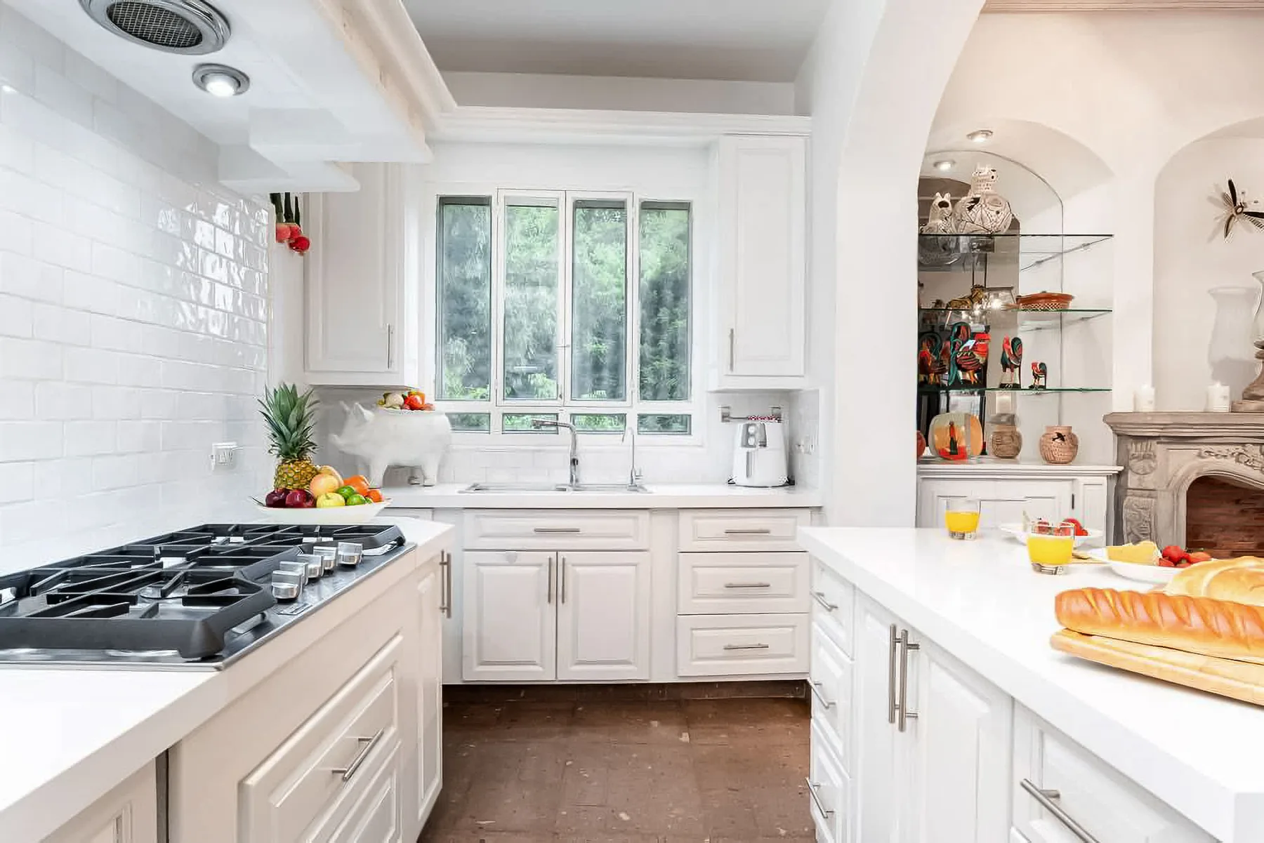 A bright white kitchen with a central island and large windows.