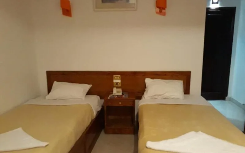 Espacio representativo del hotel: Dormitorio con dos camas y una mesita de noche de madera.