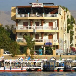 Espacio representativo del hotel: Un hotel de varios pisos se alza junto a un paseo marítimo con barcos.