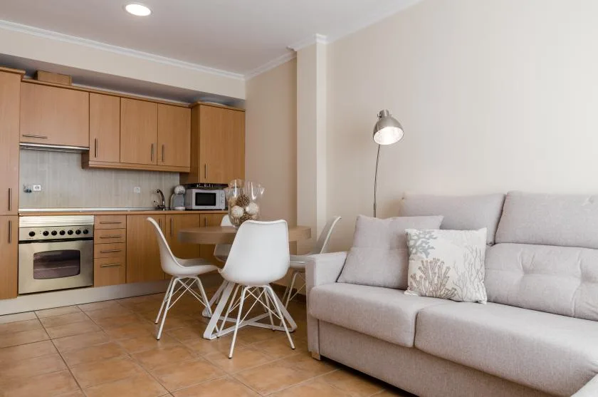 Una zona de estar con un sofá junto a una cocina compacta y una mesa de comedor.
