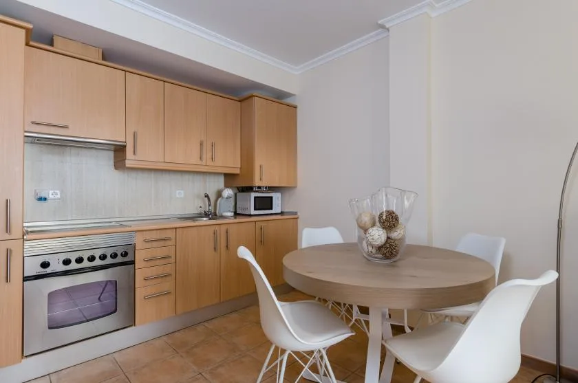 A kitchen and dining area with wooden cabinets and a round table.