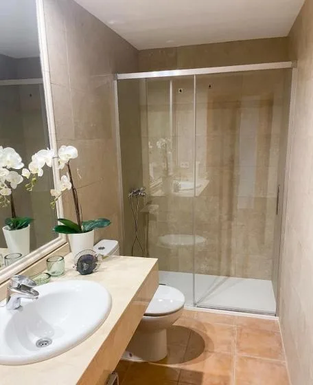 A bathroom with a sink, toilet, and glass shower.