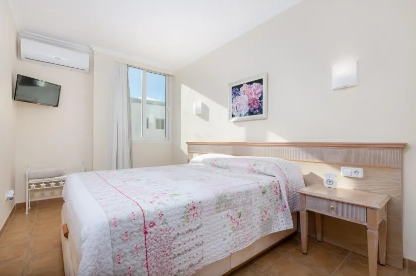 A bedroom with a bed, bedside table, and window.