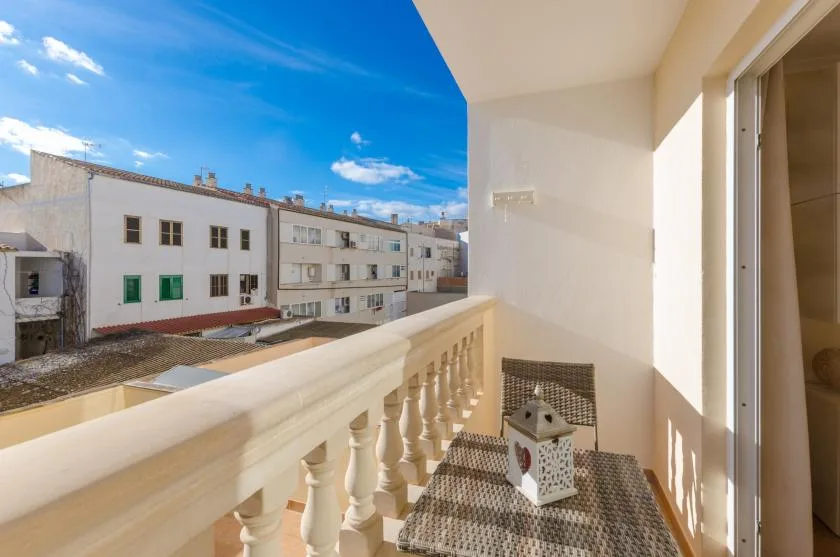 A narrow balcony overlooks nearby buildings beneath a bright blue sky.