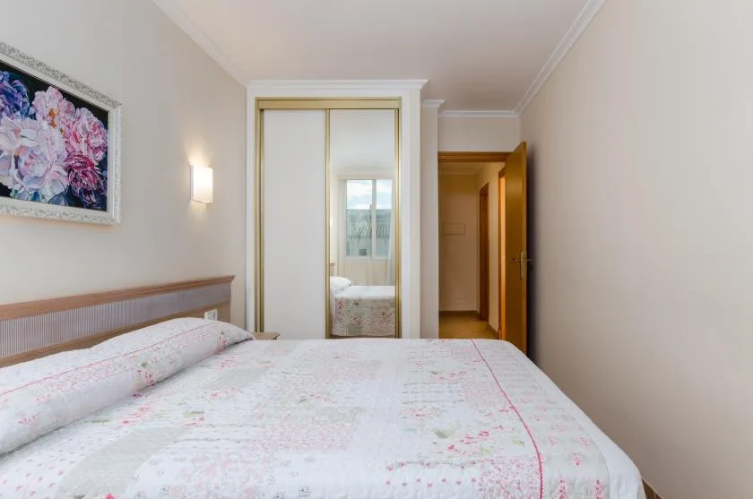 A bedroom with a bed and mirrored closet doors.