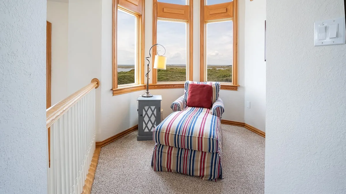A striped upholstered seat sits beside a small table in a bright window nook.