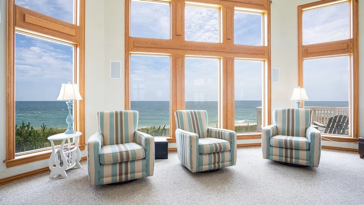 A bright sitting area with striped seating and large windows overlooking the ocean.