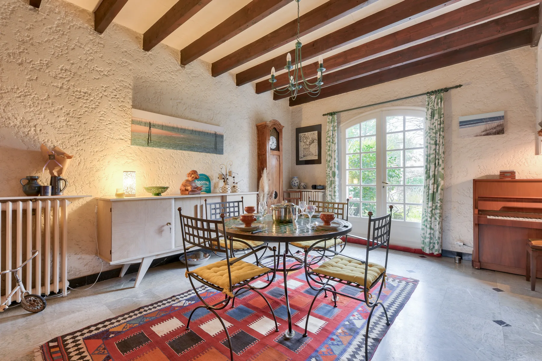 A dining area with a round table and chairs beside a large window.