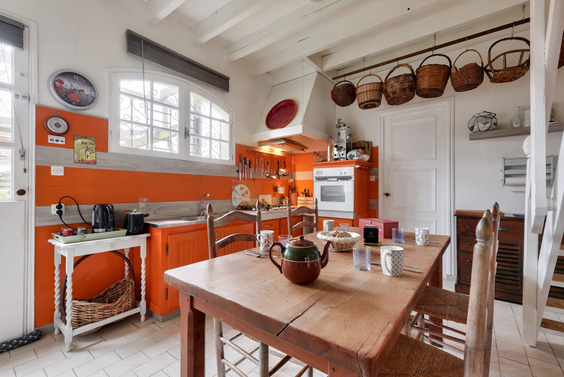 A bright kitchen with orange cabinets and a wooden dining table.