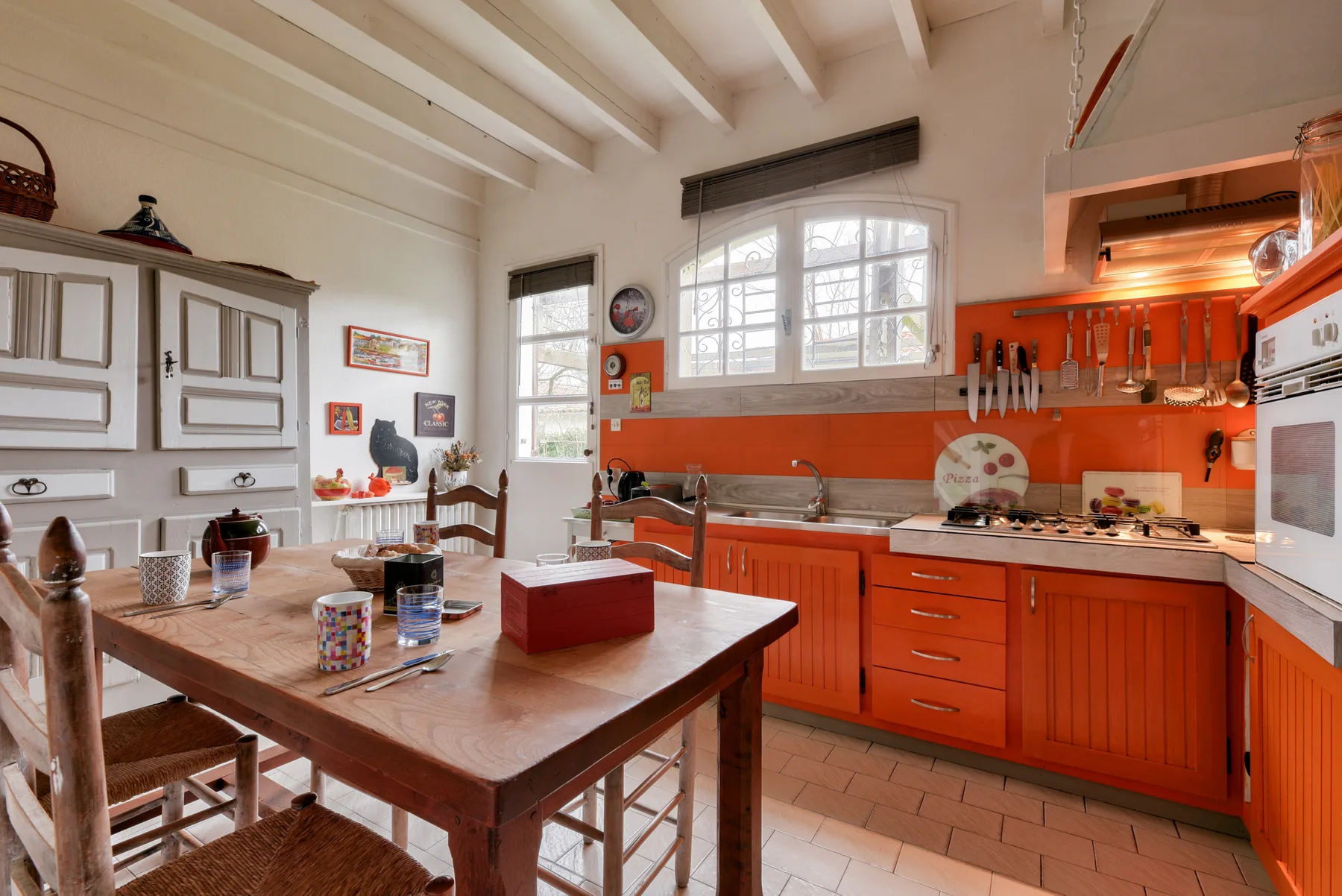 A spacious kitchen with orange cabinets, a central island, and dining table.