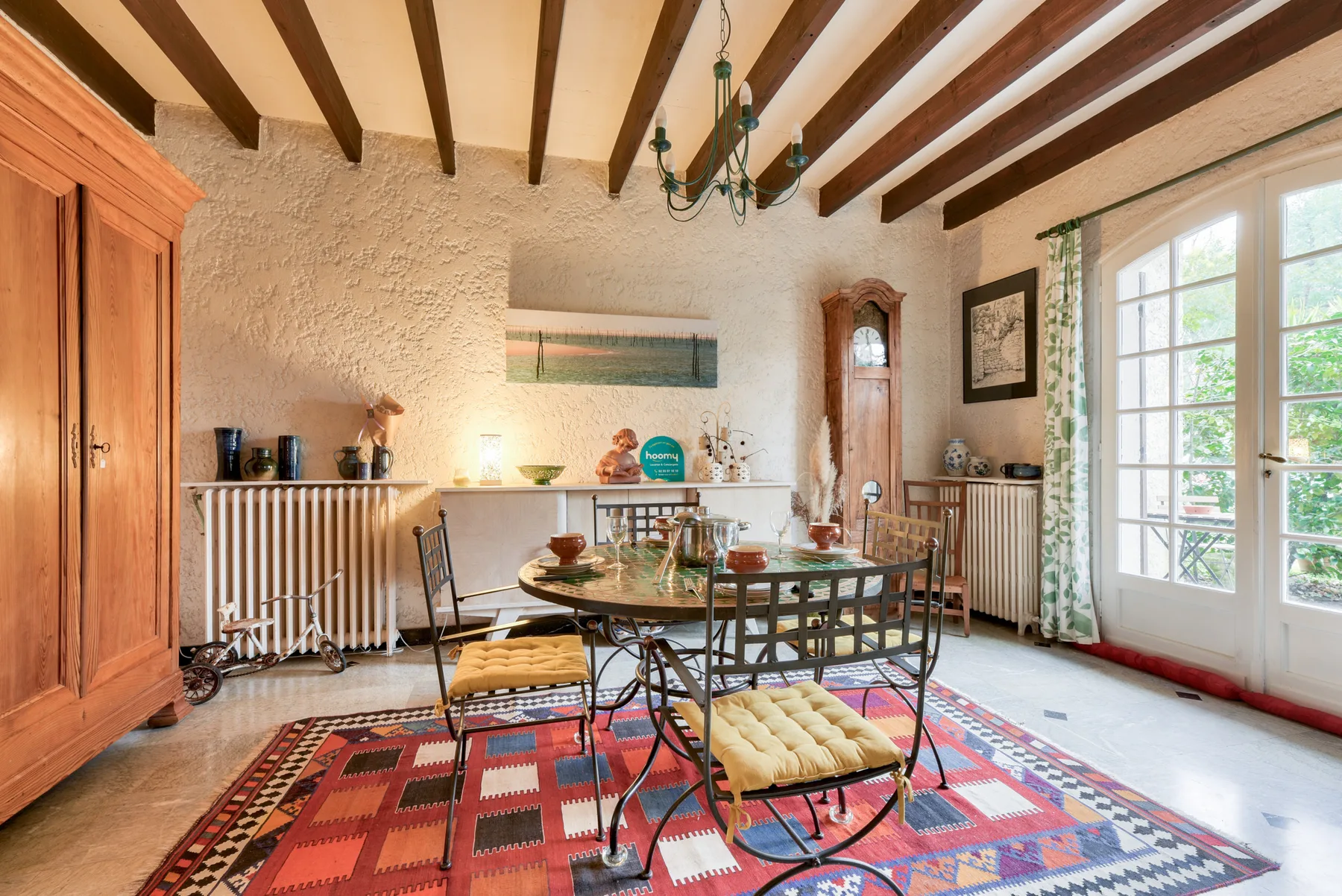 A dining room with a table and chairs on a colorful patterned rug.