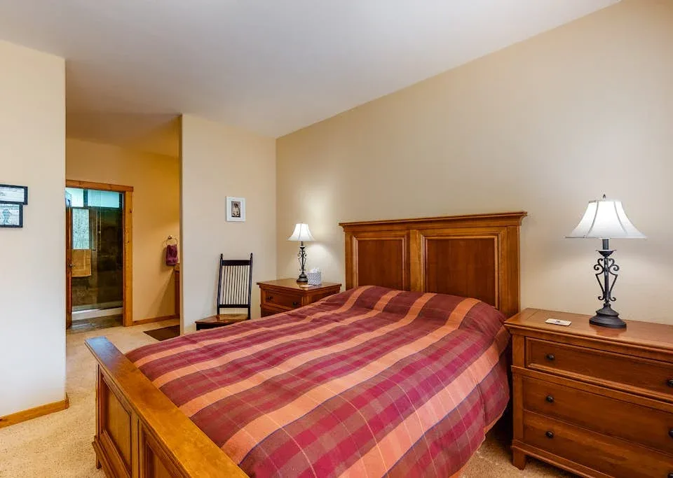 A bedroom with a wooden bed, striped bedding, and matching bedside furniture.