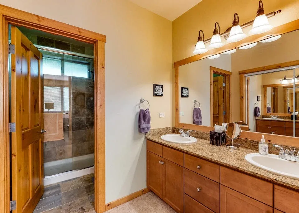 A bathroom vanity with a wide mirror beside an open shower area.