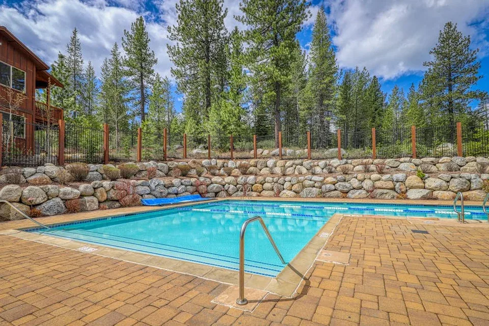 Shared amenity: An outdoor swimming pool sits beside a stone retaining wall and wooded hillside.