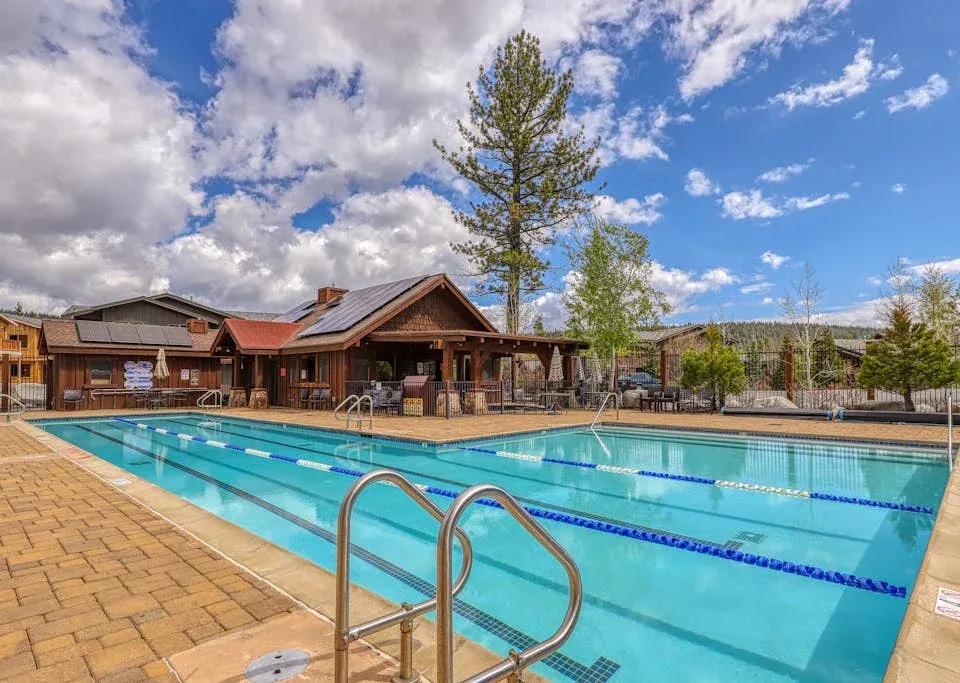 Shared amenity: Outdoor swimming pool beside a wooden building under a partly cloudy sky.
