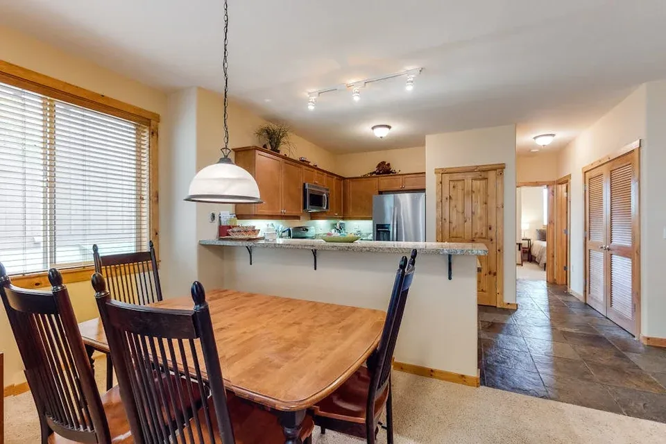 An open dining and kitchen area features a wooden table beside a breakfast counter.