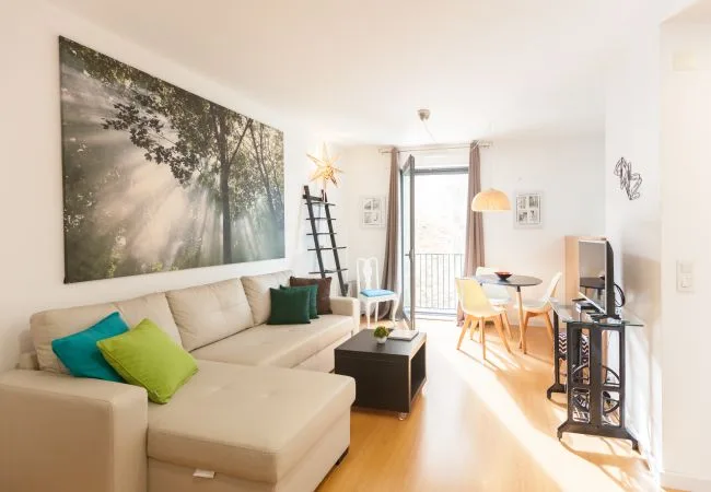 Una sala luminosa con una zona de asientos y una mesa de comedor.