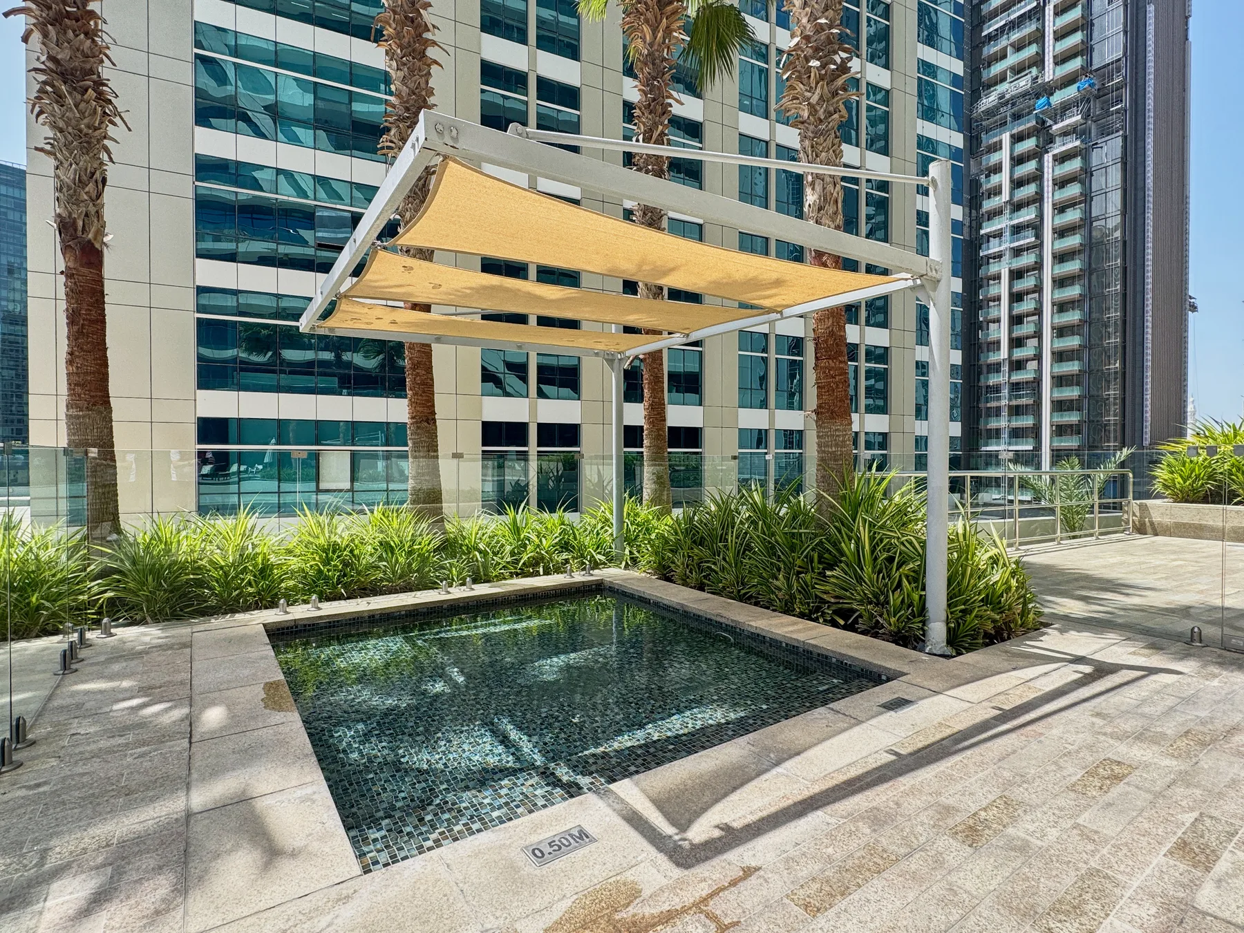 Zona común: Una piscina exterior está bajo una cubierta de sombra junto a edificios altos.