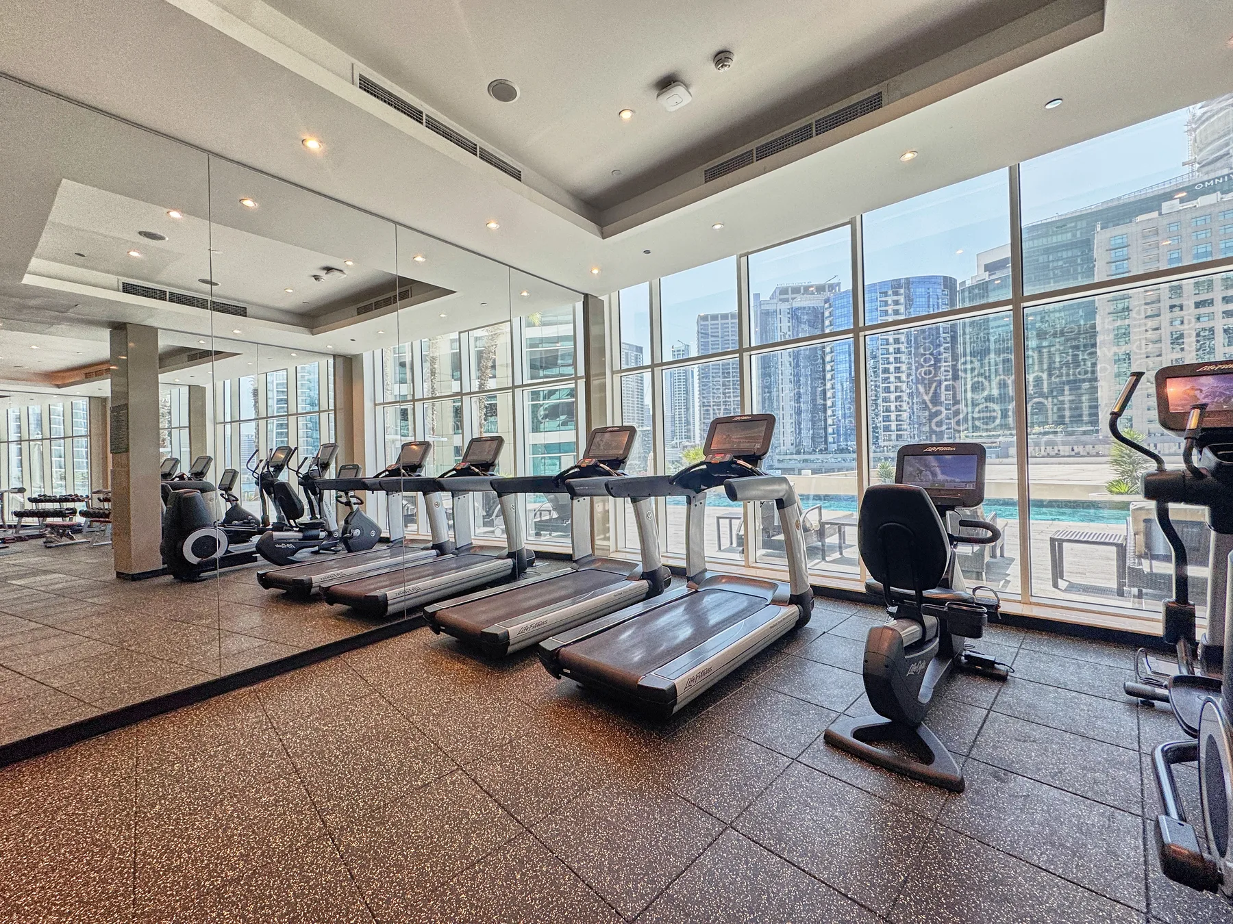 Zona común: Un gimnasio con cintas de correr y equipos de ejercicio junto a grandes ventanales.